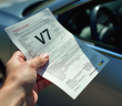Main tenant un certificat de voiture V7 au soleil