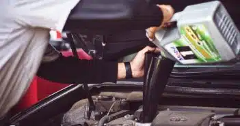 man refilling motor oil on car engine bay