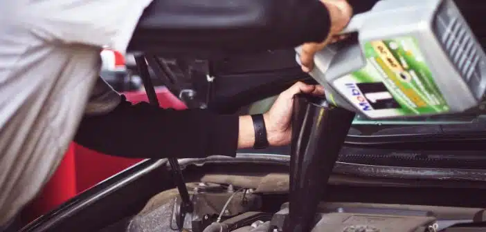 man refilling motor oil on car engine bay